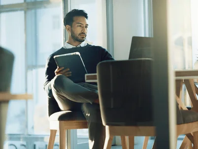 Ein Mann mit verschränkten beinen vor einem Laptop.