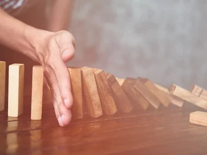 Mann stoppt mit offener Hand Dominoklötze