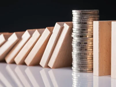 closeup auf geldmuenzen die fallende dominosteine stoppen