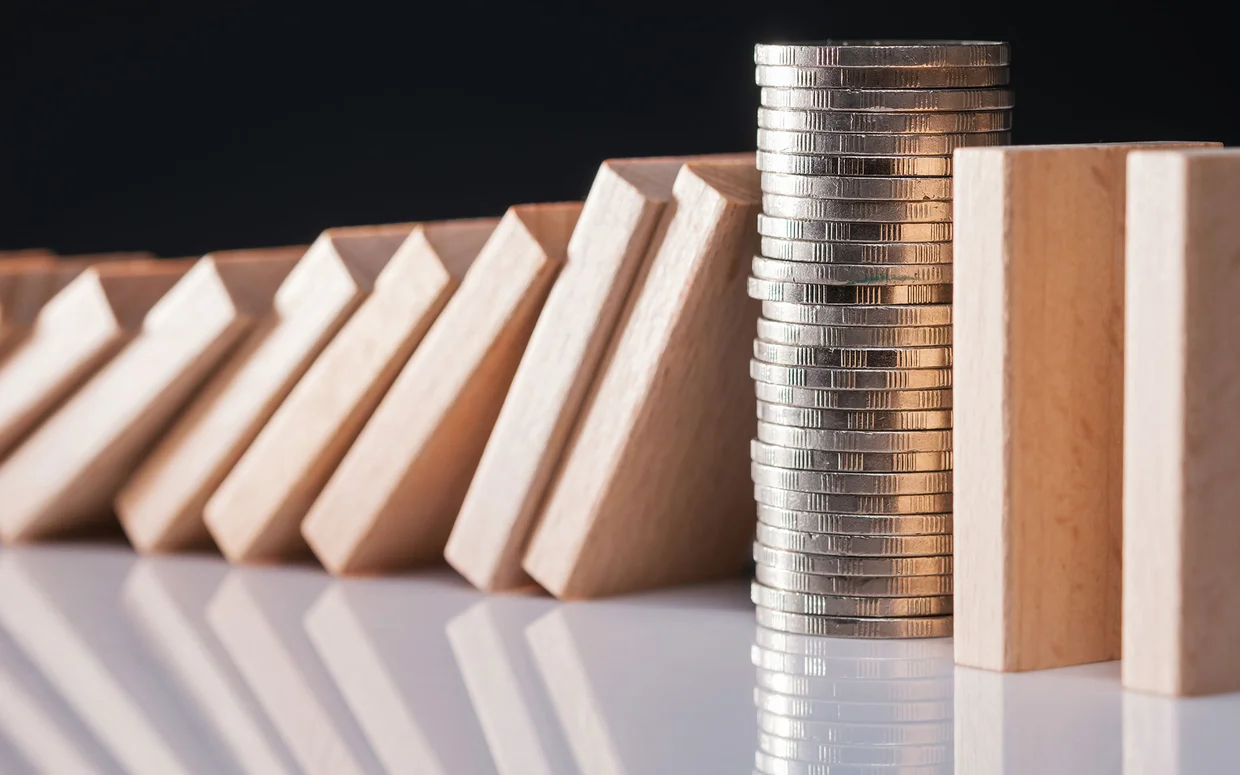 closeup auf geldmuenzen die fallende dominosteine stoppen