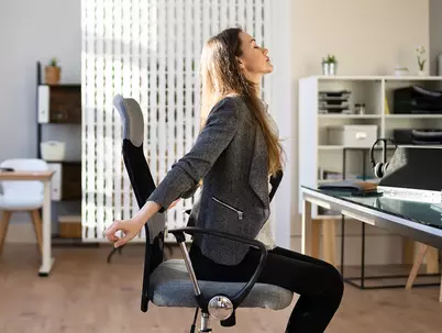 Frau streckt sich vor ihrem Arbeitsplatz im Büro