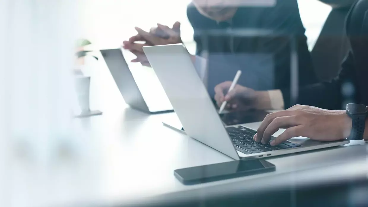 Zwei Männer sitzen vor den Laptops und besprechen sich.